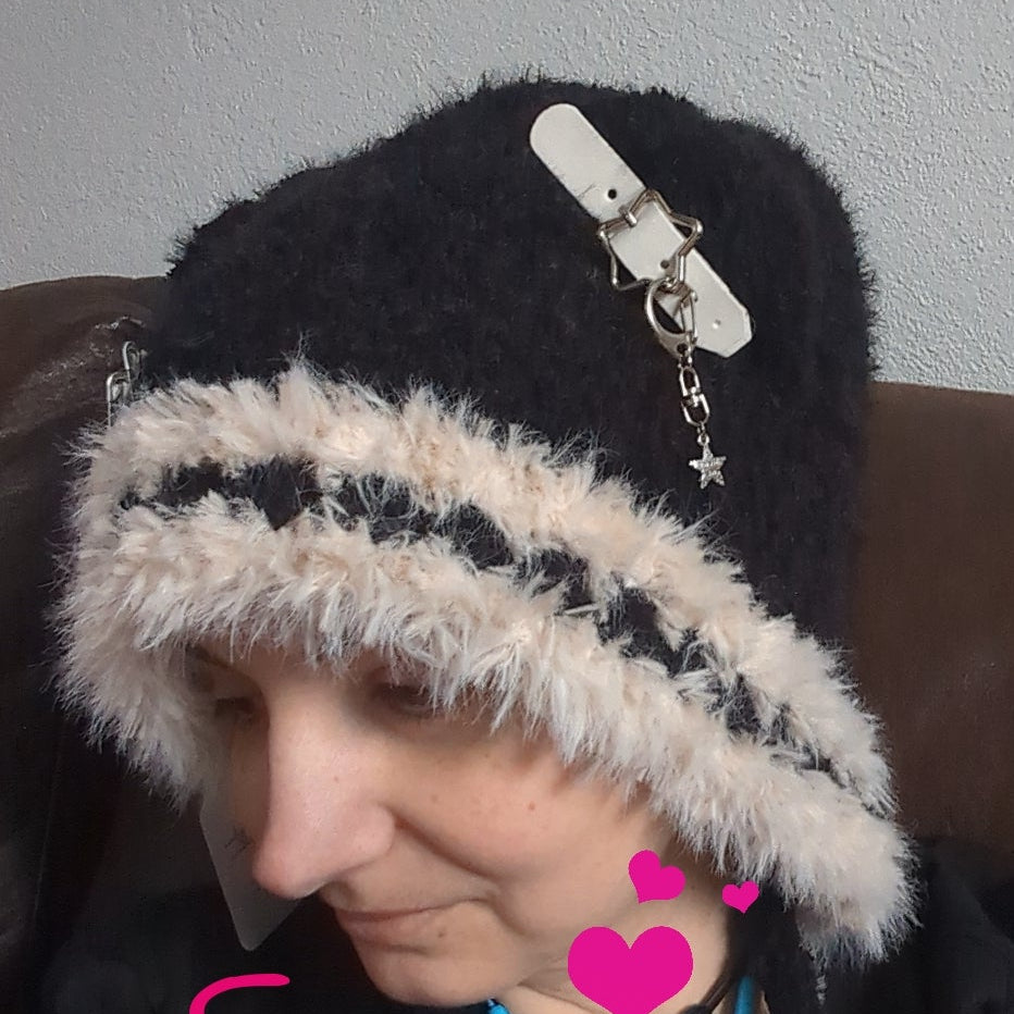 Person wearing a black and white knit hat with a decorative clip, sitting on a brown couch.